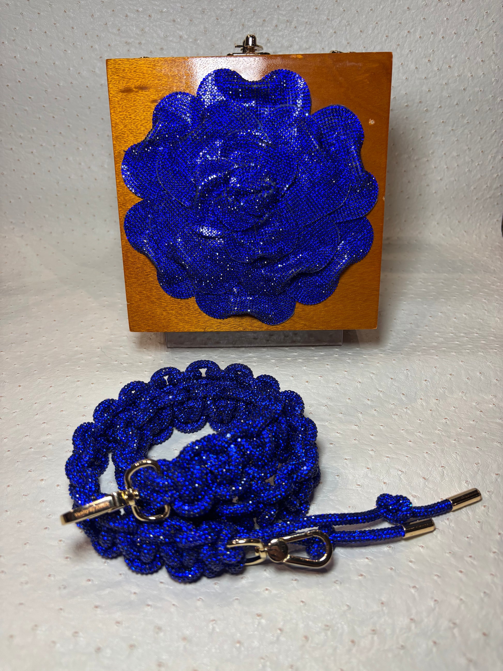 A clutch bag with royal blue rose and a matching strap.